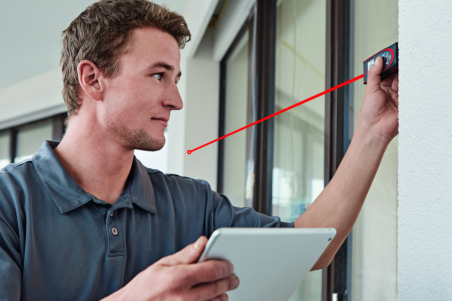 Un uomo misura la nicchia di una finestra con il misuratore laser Leica DISTO D2 e trasferisce il risultato su un tablet
