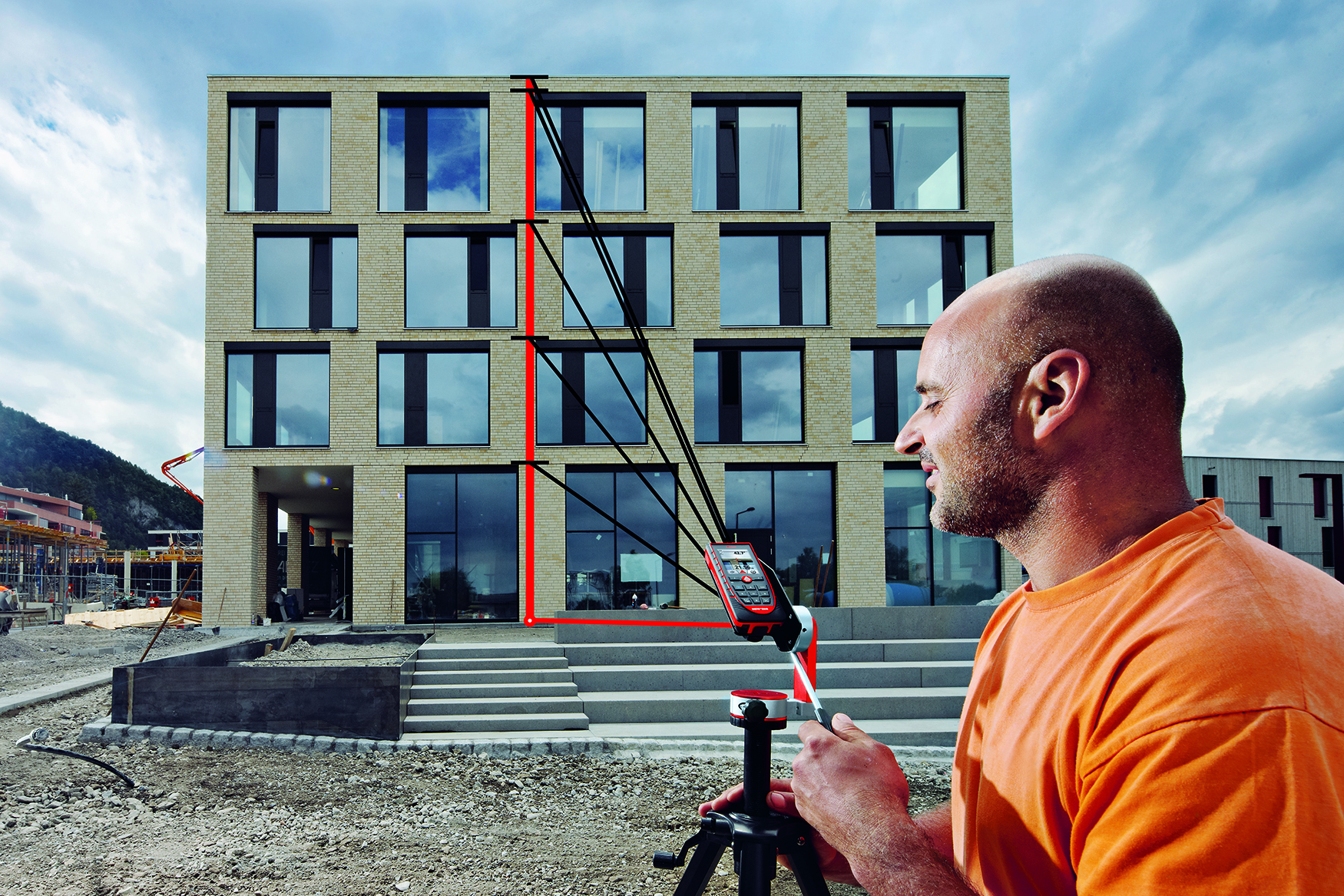 Un hombre utiliza un medidor láser Leica DISTO D510 para rastrear la altura de un edificio de varias plantas