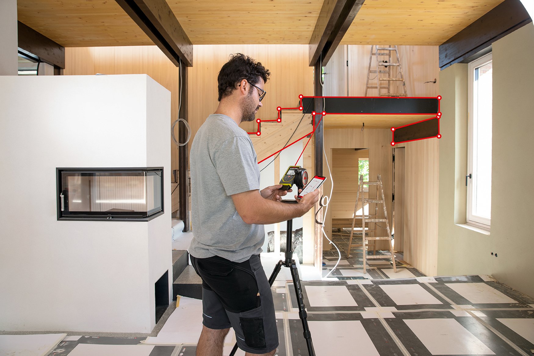 Un homme mesure les escaliers avec un laser Leica X6 sur un adaptateur de trépied DST 360-X, en utilisant la technologie P2P, et transfère les données à l'application DISTO Plan sur son Smartphone.