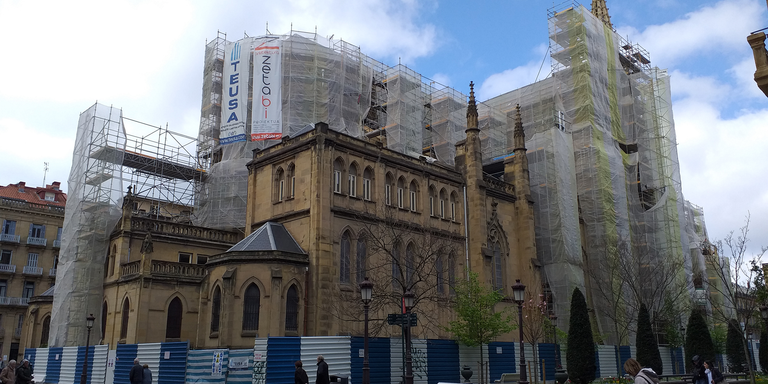 A building being constructed while individuals walk past