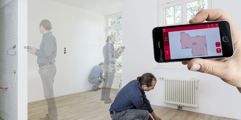 A man takes various distance measurements in a room, which are displayed as a room plan on a smartphone using the Leica DISTO Plan app. 