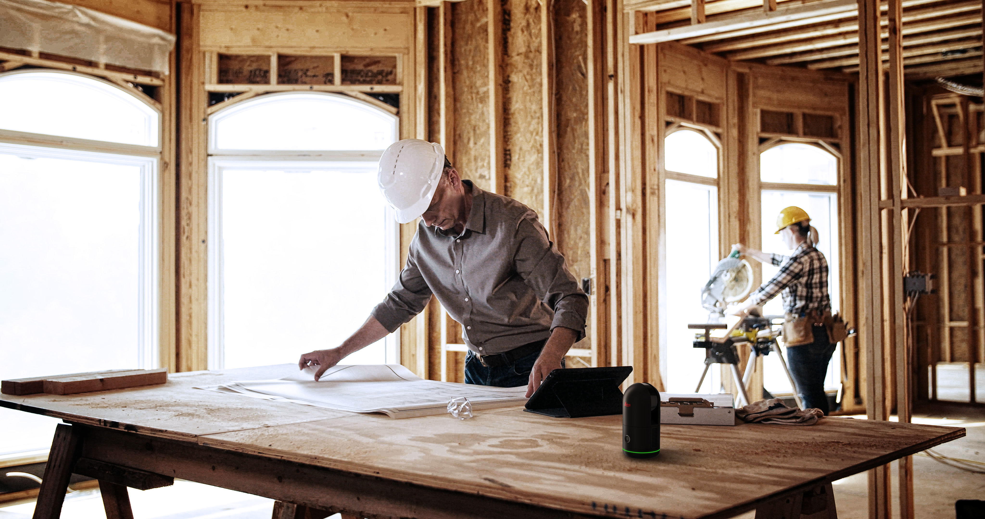Person drawing floorplans on a drafting table, with a BLK360 on the table as well